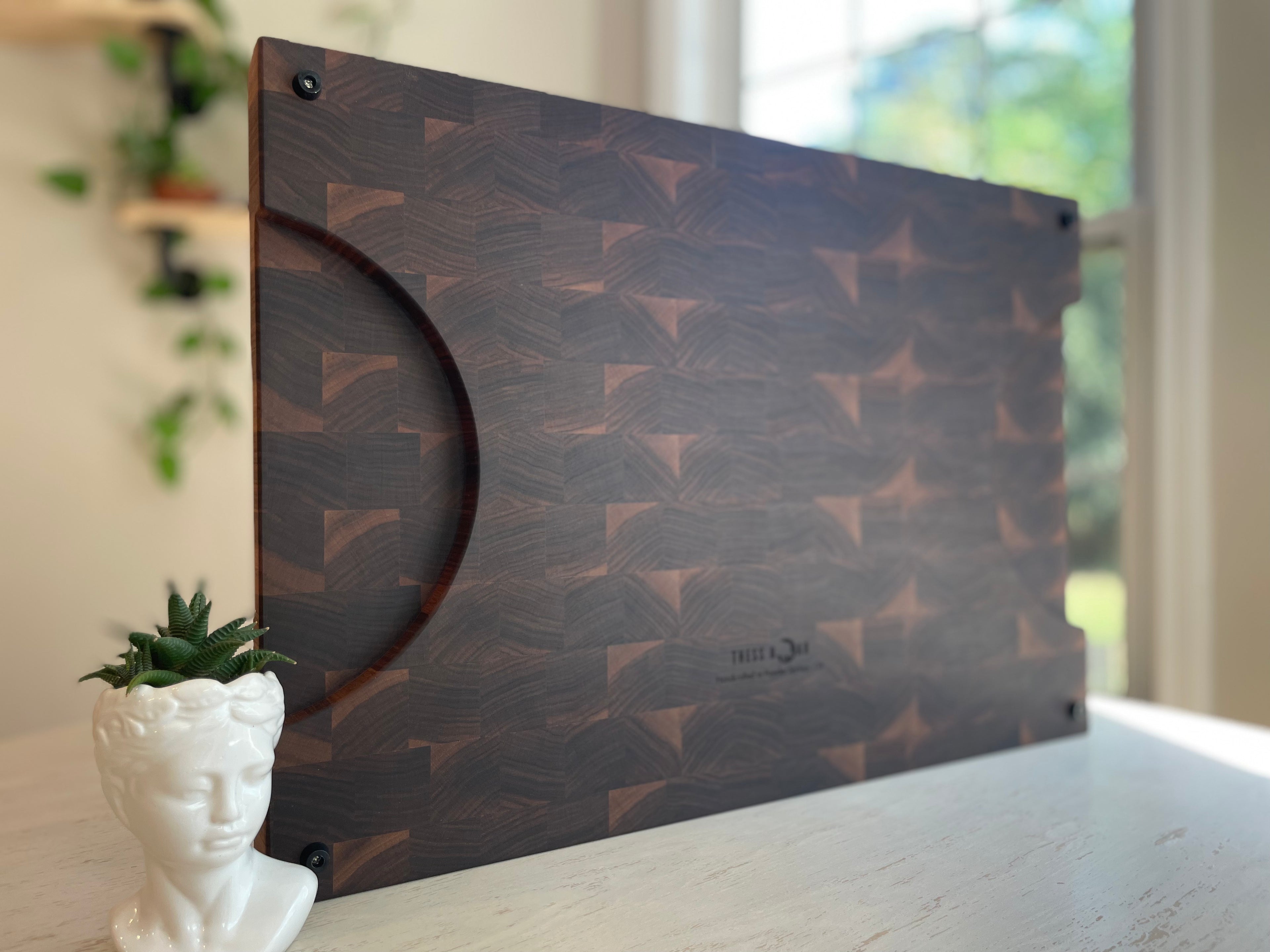 Large handcrafted walnut end grain cuttin board with distinctive geometric grain pattern and routed handle